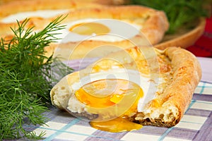 An image of an Ajarian khachapuri on table with raw egg close up