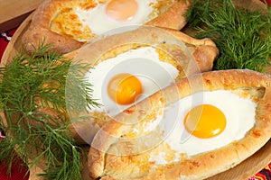 An image of an Ajarian khachapuri on table with raw egg close up