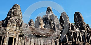 Image of the ancient Bayon Temple featuring stone towers with human faces, captured on a sunny day in Cambodia