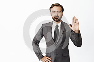 Image of angry boss, raising hand objection gesture. Denying something, saying no and tell to stop, standing over white
