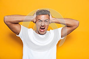 Image of angry guy 30s in white t-shirt screaming and grabbing head