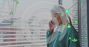 Image of asian female doctor with smartphone over media icons