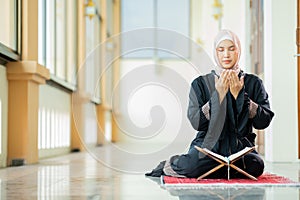 The image of an Asian Muslim woman in the Islamic religion in hijab in cream and black color. reading the Quran