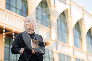 The image of an Asian Muslim woman in the Islamic religion in hijab in cream color. reading the Quran