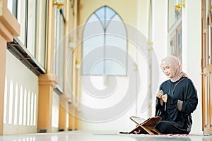 The image of an Asian Muslim woman in the Islamic religion in hijab in cream color. reading the Quran