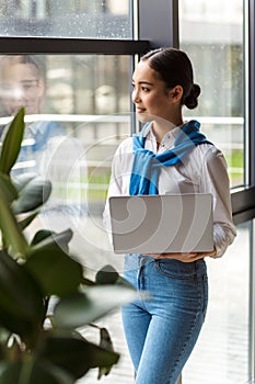 Image of asian secretary woman holding laptop computer by window