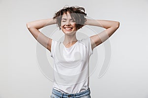 Image of attractive woman in basic t-shirt touching her hair and looking at camera
