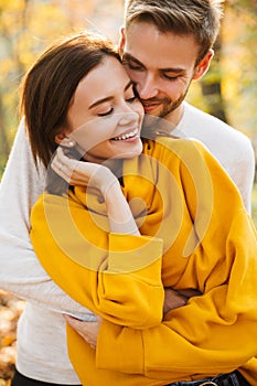 Image of attractive young caucasian couple hugging at autumn park