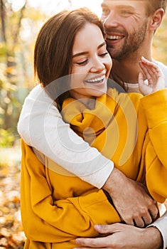 Image of attractive young caucasian couple hugging at autumn park