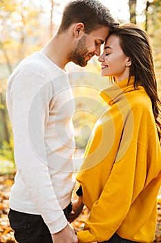 Image of attractive young caucasian couple hugging at autumn park