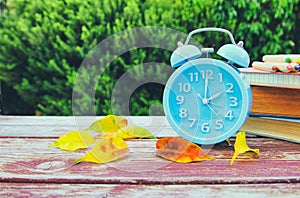 Image of autumn Time Change. Fall back concept. Dry leaves and vintage alarm Clock