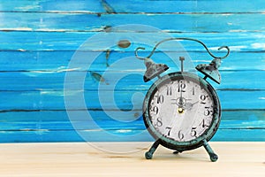 Image of autumn Time Change. Fall back concept. Dry leaves and vintage alarm Clock on rustic wooden table