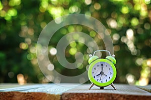 Image of autumn Time Change. Fall back concept. Dry leaves and vintage alarm Clock on wooden table outdoors at afternoon