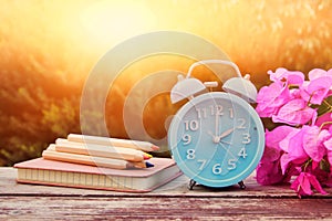 Image of autumn Time Change. Fall back concept. Dry leaves and vintage alarm Clock on wooden table