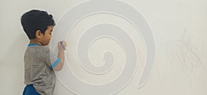 Image of a back of a asian kid  drawing creatively on white wall at her home while quarantine period of covid-19 pandemic