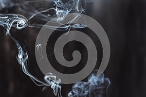 Image of backlit puffs of smoke, on a dark background. photo