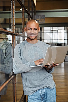 Image of bald african american man holding laptop while working in office