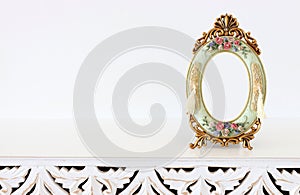 Image of baroque vintage empty photo frame over wooden table. For mockup, can be used for photography montage