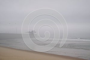 an image of the beach at the ocean shore covered in fog