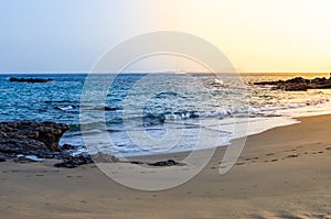 Image of a beach with a sailboat crossing the horizon