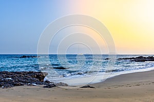 Image of a beach with a sailboat crossing the horizon