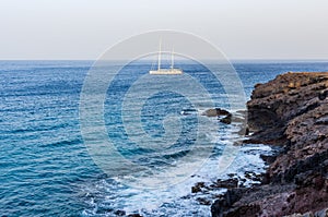 Image of a beach with a sailboat crossing the horizon