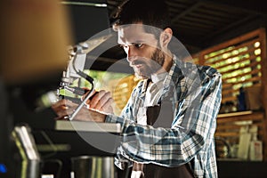 Image of bearded barista boy making coffee while working in cafe or coffeehouse outdoor