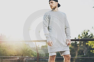 Image Bearded Muscular Man Wearing Gray Empty sweetsh, snapback cap and shorts in summer holiday. Chilling time near the