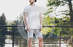 Image Bearded Muscular Man Wearing White Empty t-shirt, snapback cap and shorts in holiday. Chilling time near the lake