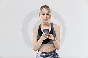 Image of beautiful blond woman 20s dressed in sportswear using smartphone during workout in gym