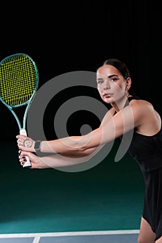 Image of a beautiful female tennis player in a black dress posing on the tennis court. Sports concept