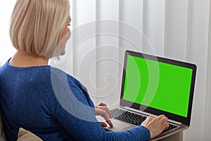 Image of beautiful joyful woman smiling while working with laptop at home