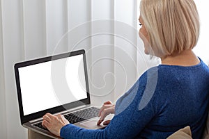 Image of beautiful joyful woman smiling while working with laptop at home