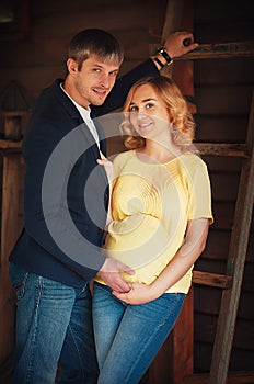 Image of beautiful pregnant woman and her handsome husband hugging the tummy