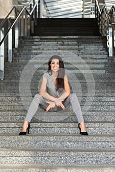 Image of beautiful stylish woman sitting on street stairs joking