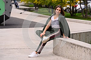 Image of beautiful stylish woman sitting on street stairs with legs crossed on summer day