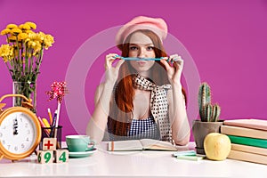 Image of beautiful teenage girl studying with exercise books while sitting at desk