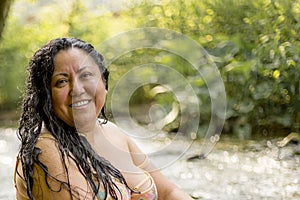Head shot portrait of a Chubby Mexican woman smiling at the camera with green vegetation