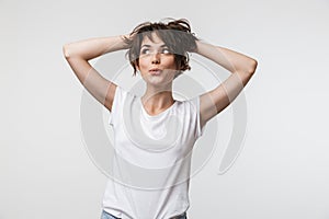 Image of beautiful woman with short hair in basic t-shirt smiling and grabbing her head