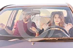 Image of beautiful woman at wheel learns to drive, her husband sits at front seat, young family look frightened, have some road