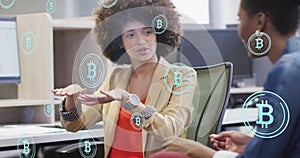 Image of bitcoin symbols over diverse colleagues discussing work in office