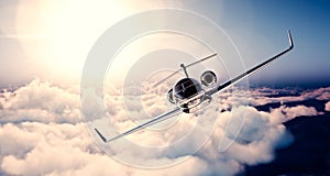 Image of black luxury generic design private jet flying in blue sky at sunset. Huge white clouds background. Business