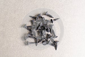 Image of black metal screw pile on the gray background. wood screws made of steel. Group of new strong black screws.