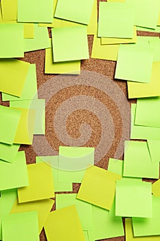 Image of blank green and yellow sticky notes on cork bulletin bo