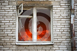 Image of brick house with with fire in window.