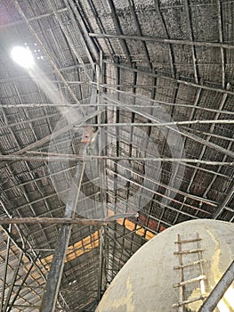 bright smoke streaming from charcoal kiln outlet to the ceiling attap roof hole. photo