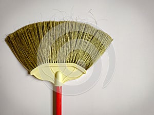 image of broom with plastic bristles with some hairs attach to it and handle in vintage background