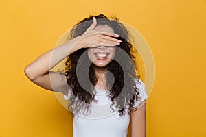 Image of brunette woman 20s with curly hair smiling and covering