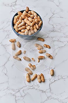 Image of bunch of peanuts in a bowl on a marble table