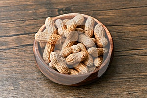 Image of bunch of peanuts in a bowl on a wooden table